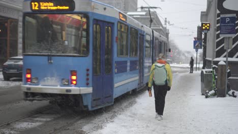 Tram-And-Pedestrians-In-The-Street-During-Snowfall-In-Oslo,-Norway-On-A-Cold-Winter-Day