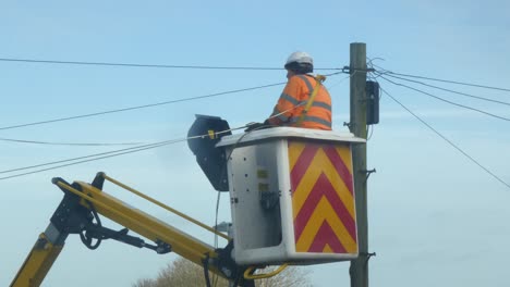 Telecom-technician-working-repairing-telephone-pole-power-cable-in-boom-crane-bucket