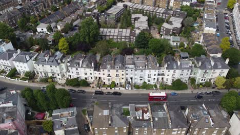 Red-london-bus-passing-row-of-terraced-house-Primrose-hill-London-,-drone-aerial-view