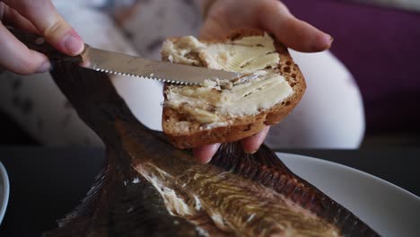 Person-making-delicious-fresh-fish-sandwich-with-kitchen-knife,-close-up