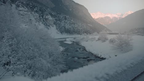 River-in-winter-landscape,-high-alpine-mountains-in-background