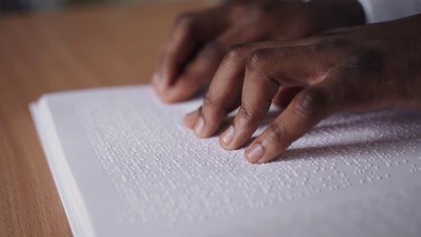 Close-up-of-blind-person-reading-a-book-in-braille-with-his-hands,-blindness-concept-background