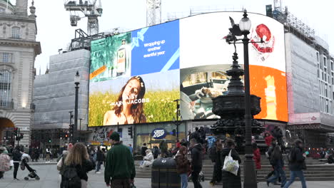 Advertisements-on-big-screens-in-Piccadilly-Circus,-London-with-Christmas-crowds-of-people