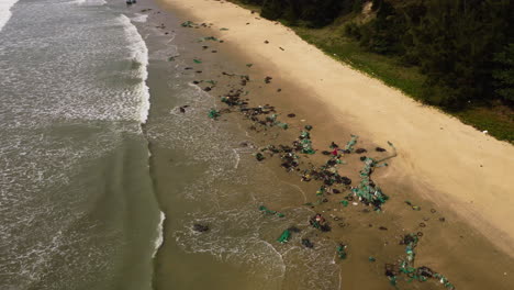 Aerial-view-of-tropical-sandy-beach-in-Vietnam-with-plastic-fishing-net-washed-out-after-thyphoon-storm-during-monsoon-season,-ocean-pollution-climate-change-concept