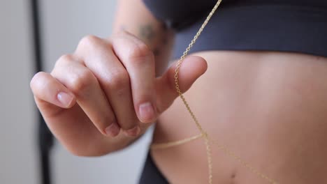 Young-woman-slowly-touching-her-gold-necklace-accesory,-macro-shot-in-close-up-view,-indoors-video