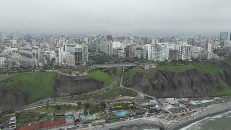 Onshore-aerial-of-clifftop-and-beach-traffic-in-dense-cloudy-Lima-Peru
