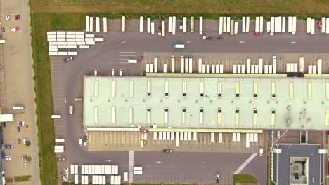 Luftbild-Von-Oben-Nach-Unten-Auf-Den-Großen-Logistikpark-Mit-Lagern,-Ladehub-Und-Vielen-Sattelschleppern-Mit-Frachtanhängern,-Die-Darauf-Warten,-Waren-Auf-Rampen-Zu-Entladen