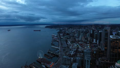Aerial-pulling-away-from-Seattle's-waterfront-corridor-on-a-dark-and-cloudy-morning