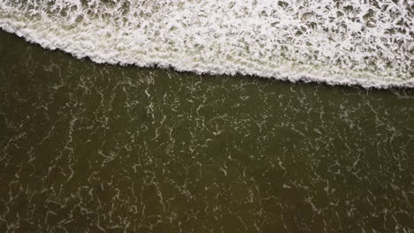 Meereswellen-Rollen-In-Richtung-Sandstrand-Mit-Ausgewaschenen-Fischernetzen,-Luftaufnahme-Von-Oben-Nach-Unten