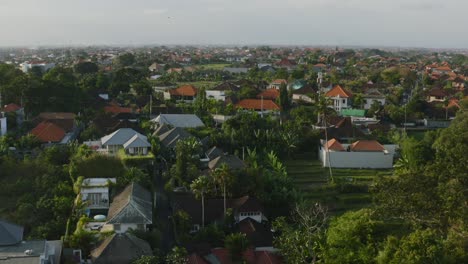 Luftaufnahme-Eines-Wohngebiets-Bei-Sonnenuntergang-Auf-Bali,-Indonesien,-Umgeben-Von-Reisfeldern
