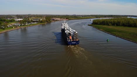 Aerial-Stern-View-Of-Symphony-Provider-Cargo-Ship-Transporting-Transporting-Wind-Turbine-Propeller-Blades-Along-Oude-Maas