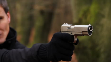 Close-up-of-criminal-firing-a-pistol-in-a-forest