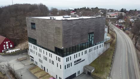 Kuben-museum-and-archives-in-Arendal-Norway---Closeup-aerial-moving-backward-and-revealing-full-exterior-with-city-background