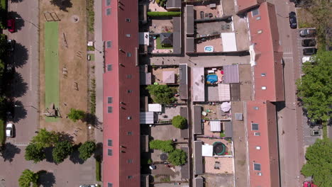 Aerial-birds-eye-overhead-top-down-of-a-dutch-neighborhood-with-two-rows-of-terraced-houses-and-adjacent-gardens-and-a-playground