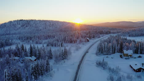 Aerial-view-above-fairy-tale-sunrise-Scandinavia-mountain-with-vehicle-on-journey-travelling-snow-covered-woodland