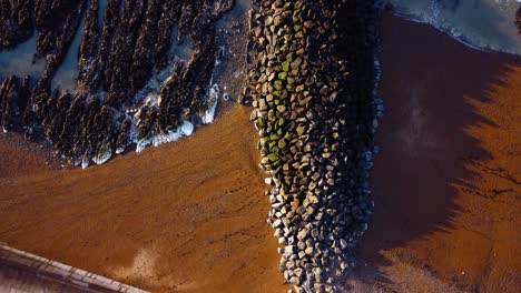 Klare-Und-Helle-Luftaufnahmen-Von-Wellen,-Die-An-Einem-Sonnigen-Tag-An-Einem-Britischen-Strand-Auf-Felsen-Krachen