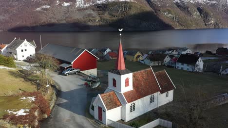 Ancient-Stave-Church-of-Undredal-along-Aurlandsfjord-in-Norway---Aerial-showing-Europes-smallest-stavechurch-during-sunrise