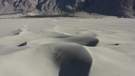 Luftdrohne-Kreist-An-Einem-Sonnigen-Sommertag-Links-In-Den-Sanddünen-Der-Kalten-Wüste-In-Skardu,-Pakistan,-Mit-Den-Felsigen,-Einsamen-Bergen-Im-Hintergrund
