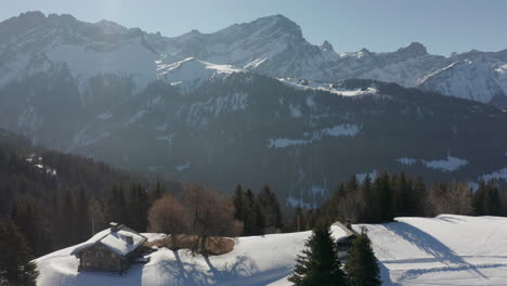 Luftaufnahme-Eines-Wunderschönen-Tals,-Drohne-Zieht-Sich-Zurück-Und-Enthüllt-Kleine-Hütten-In-Einer-Schneebedeckten-Landschaft