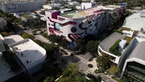 Aerial-view-towards-an-artsy-design-district,-museum-garage-parking-lot,-in-Wynwood,-Miami,-USA---tilt,-drone-shot