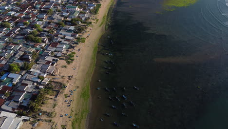 Coastal-seascape-town-with-living-building-and-many-water-ponds-for-shrimp-farming-nearby,-aerial-view