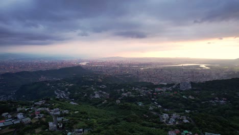 Overlooking-Taipei,-Taiwan-from-a-mountain-during-dramatic-cloudy-sunset---Drone-Forward-push