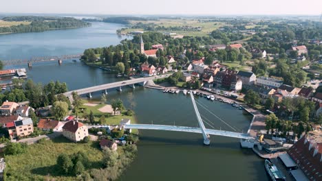 Mikolajki,-Poland---An-drone-round-flight-aerial-bird-view-starting-at-the-pedestrian-bridge-most-wiszacy-and-rotation-over-the-panorama-of-the-touristic-city-in-Warmian-Masurian-with-blue-lake