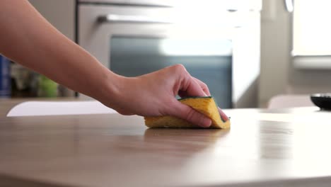 Mujer-Limpiando-La-Mesa-De-La-Cocina-Con-Una-Esponja-Amarilla