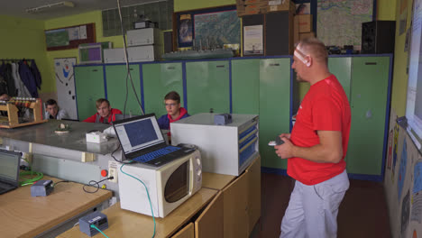 Vocational-high-school-teacher-presenting-to-a-classroom-full-of-young-male-students-sitting-and-listening-at-their-computers