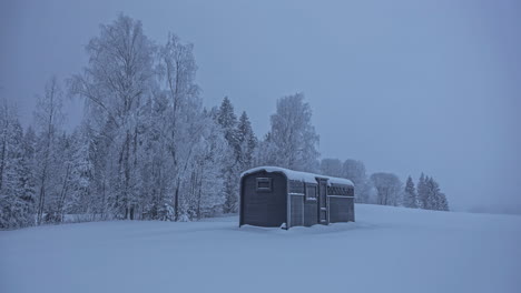 Zeitrafferaufnahme-Eines-Dunkelgrauen-Wintertages-Mit-Schneebedecktem-Feld-Und-Holzhaus-In-Der-Natur