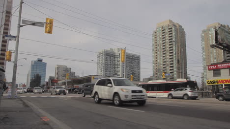 Zeitraffer-Zeitraffer-Der-Innenstadt-Von-Yonge-Street-In-Toronto,-Autos,-Die-Menschen-über-Straßen-Fahren,-Und-Hohe-Gebäude-Im-Hintergrund-Einer-Stadt
