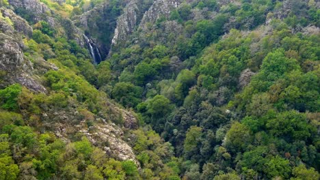Aerial-Circle-Dolly-Around-Forest-Ravine-To-Reveal-Fervenza-do-Toxa-Waterfalls-In-Distance