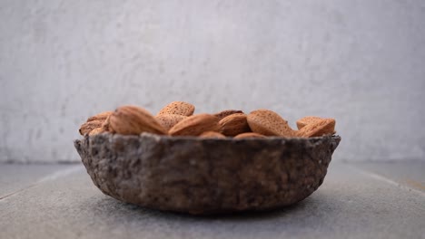 Almond-Nuts-In-Shell-Falling-On-Wooden-Bowl
