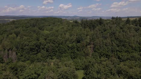 Aerial-footage-of-soft-cumulus-clouds-over-a-lush-green-thicket-of-deciduous-trees-in-the-German-countryside