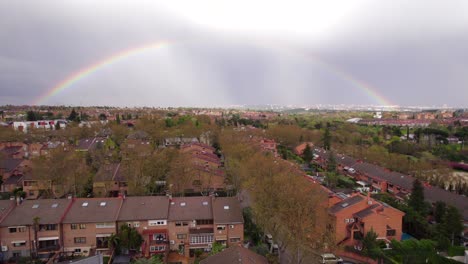 Full-rainbow-after-a-stormy-day-over-suburbs-in-Pozuelo,-Madrid,-Spain