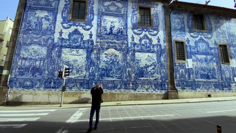 Toma-En-Cámara-Lenta-De-Turista-Tomando-Fotos-De-Azulejos-Estampados-Azules-En-Una-Pared-En-La-Carretera-En-Porto,-Portugal