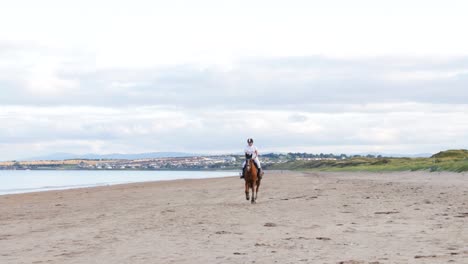 A-beautiful-girl-with-long-hair-rides-her-horse-on-the-beach-during-the-evening-in-Donabate,-Ireland