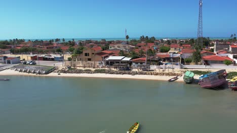 Barcos-De-Pesca-Flotando-En-El-Mar-Con-Casas-Frente-Al-Mar-En-Verano-En-Galinhos,-Rio-Grande-Do-Norte,-Brasil