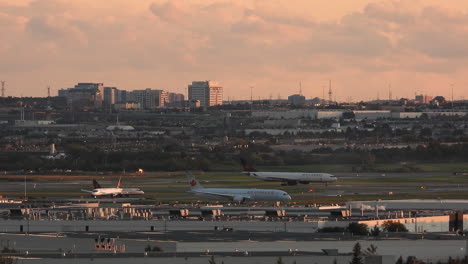 Toronto's-Comercial-Airport-scenery,-planes-in-a-row-for-takeoff-with-city-in-background