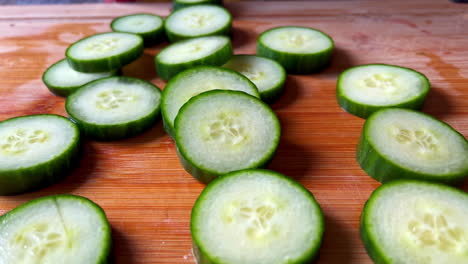 Closeup-of-Freshly-Sliced-Cucumbers-On-Wood-Cutting-Board,-Slow-Movement