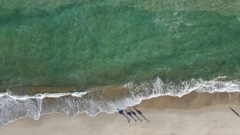 Shadow-of-friends-with-surfboard-walking-on-beach