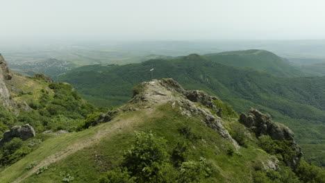 Birdseye-shot-of-the-forested-Azeula-hill-and-fortress,-and-a-Christian-cross