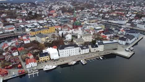 Approaching-landmark-trinity-church-in-Arendal-Norway---Aerial-from-seaside-towards-Tyvholmen-and-city-center