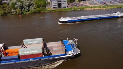Missouri-Cargo-Vessel-Passing-An-Unloaded-Freight-Vessel-Sailing-By-Oude-Mass-River-From-Zwijndrecht,-The-Netherlands