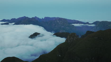 Drohnenansicht-Von-Wolken,-Die-Das-Bergplateau-Hinunter-Ins-Untere-Tal-Fließen