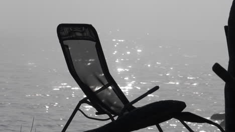 Silhouette-of-sun-lounger-in-front-of-hazy-sea,-slow-motion