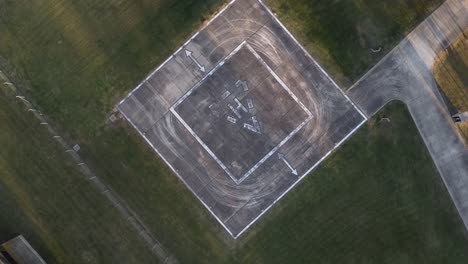 Aerial-drone-top-down-circling-view-of-empty-heliport-for-helicopter-in-green-meadow