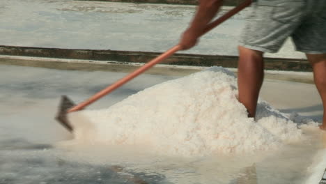 Close-up-of-a-man's-arms-pulling-and-gathering-salt-with-a-wooden-shovel---rasoila