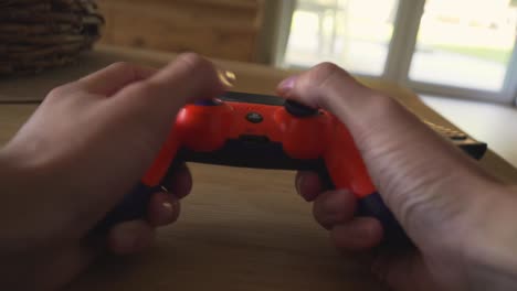 Ein-Typ-Spielt-Eine-Playstation-Mit-Einem-Orangefarbenen-Controller