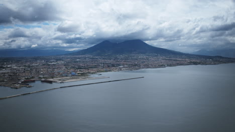 Aerial-hyperlapse-of-clouds-flying-over-Mount-Vesuvius-while-boats-drive-past-on-the-water
